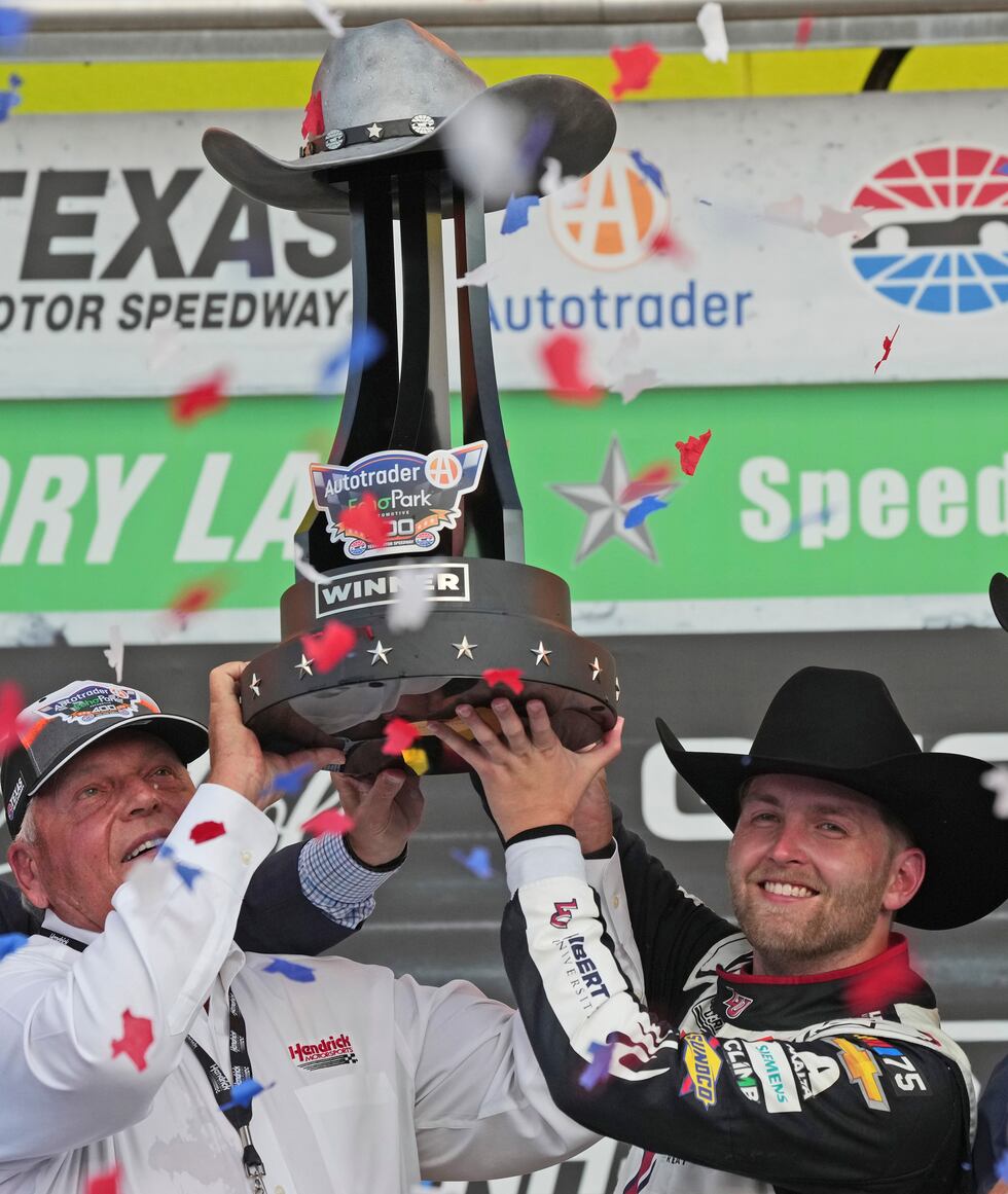 William Byron, right, and team owner Rick Hendrick hold up the trophy after winning the NASCAR...