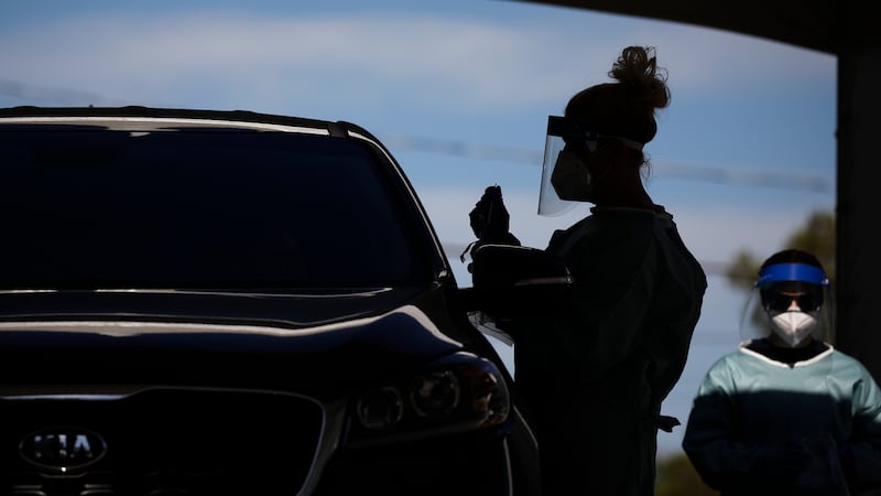 In this July 10, 2020, file photo healthcare workers test patients in their cars at a...